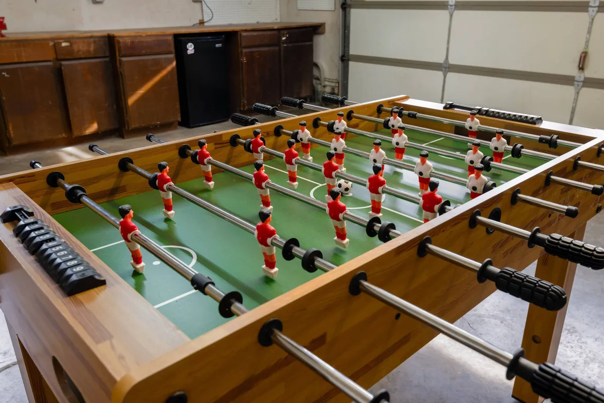 This image features a foosball table set up in a lounge-like space with bright lighting and a wooden surface, emphasizing a playful, social environment ideal for group activities.